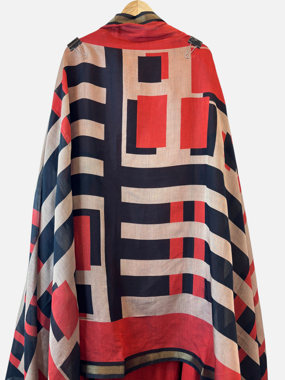 Design by Pakiza Maheshwari unstitched suit fabric with a bold red, black, and beige geometric print and gold border